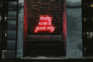 A neon sign on a brick wall that reads “today was a good day”