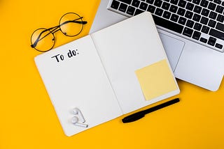 A notebook and a computer on a yellow desk