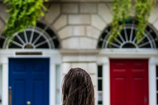 a woman is in front of a blue and red door and feels she must choose