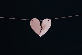 a broken pink paper heart on a string