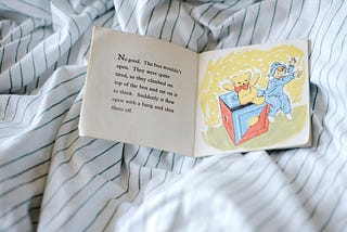 A children’s book open on a striped sheets.