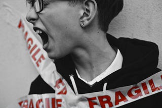 A yelling person taped to a wall. The tape reads “fragile.”
