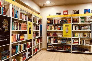 Shelves of books, and two posters, in a bookstore.