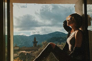 Young woman overlooking the hillside of Majorca from a window ledge