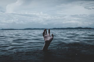 Cloudy sky and a hand reaching out of body of water