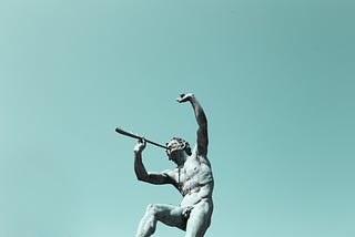 Statue of nude man playing an instrument raising a fist in the air.