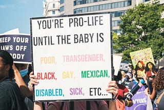 Pro-abortion rally with protestor holding sign that reads: You’re pro-life until the baby is poor, transgender, Black, gay, Mexican, disabled, sick, etc…”