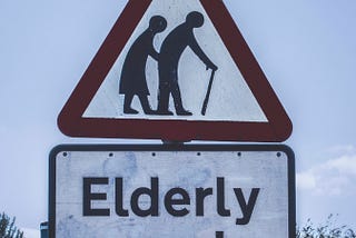 the picture of the couple , backs bent, man with walking stick warning traffic of elderly folks