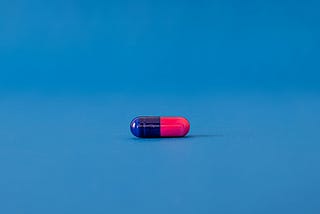 A medicine capsule, one half red, one half blue.