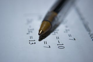 A pen lying on a white sheet of paper with some equations on it