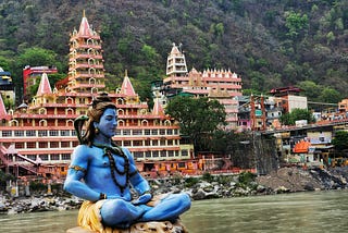 Image of the Ganges River with a statue of a blue god in the foreground.