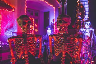 Colour photo of a pair of life-size decorative skeletons outside a house decorated for Halloween