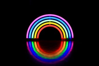 A neon rainbow, which is also reflected in the surface below