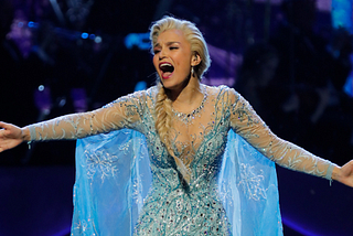 Samantha Barks performing as Elsa from Frozen, her mouth open and arms outstretched