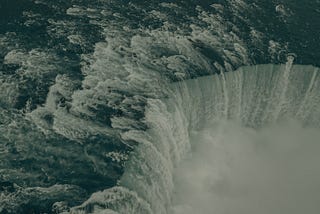 A giant waterfall pictured from far above the rushing waters and fog rising from the chasm.