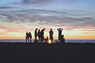 a group of people enjoying a bonfire at sunset