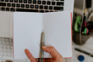 An open, blank sketchbook with a computer keyboard in the background