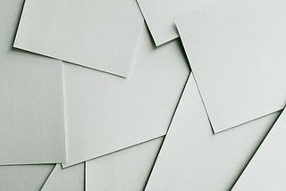 Many pieces of white paper on a table, just strewn about.