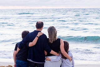 Family with back turned looking at the lake. Mother, father and two children