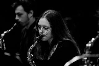 A picture in black and white of Keyana, a brown haired girl with hazel eyes, playing the saxophone.