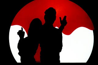 A silhouette of two people inside a bubble, holding up their fingers like guns.