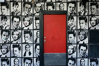 A wall full of black and white photos of actors with a red door in the middle.