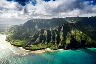 Hawaii. A lush green mountain set against the turquoise sea.