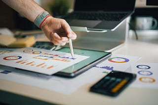Hand pointing to chart on paper with a calculator next to it