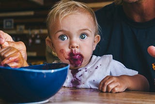 An infant is making a mess eating pie.