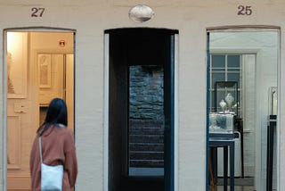 A young woman facing three open doorways to homes.