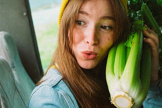 Woman holding a bunch of celery to her cheek
