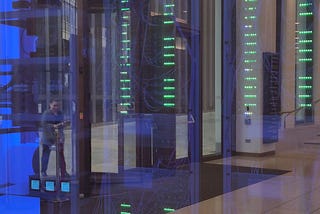 Glowing blue glass box with a complex of wires, electrical equipment, and columns of green lights