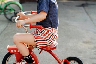 young boy on tricycle with impishe grin on his face