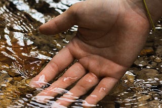Right palm with water gently flowing over the fingertips.