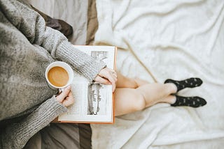 a person sitting with a book and a cup of coffee