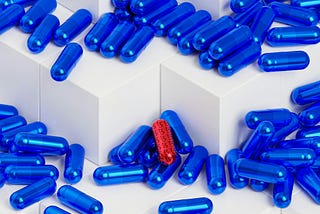 a red capsule among many blue capsules on white cubes