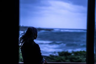 Lone woman staring at the ocean at dusk
