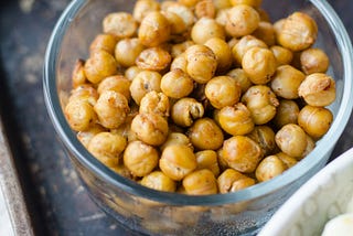 close up on a glass bowl filled with roasted, seasoned chickpeas