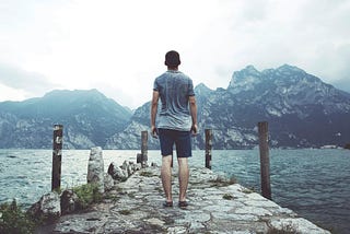 A man stands at the edge of a path representing embarking on commitment, courage, and compassion for spiritual growth
