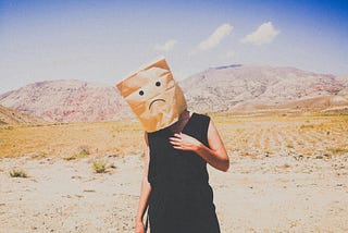 Person with a sad face paper bag over their head