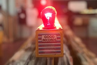 A red light bulb illuminated above a sign reading “good records”
