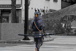 A samurai warrior walking in a modern day crosswalk.