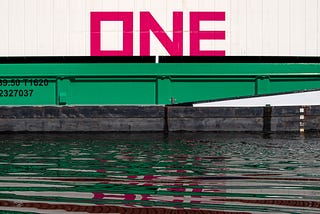 Huge red letters that spell “ONE” sitting on top of a freight car.