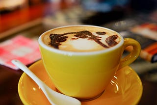 Coffee in yellow mug with white spoon.