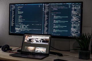 laptop computer in front of a large monitor