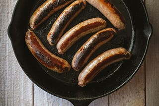 Close up of a frying pan of burnt sausages