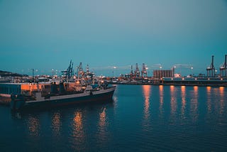 A ship docked in a port with lights reflecting on the water.