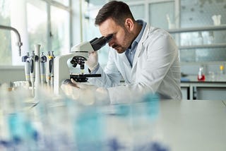 Male researcher analyzes sample under microscope — Invitae blog