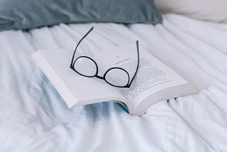 A pair of glasses atop an open book.