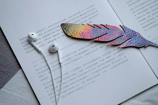 A quill-shaped cutout and headphones on a printed page